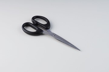 Black metal scissors on a white background with studio lighting
