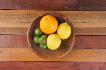 various types of oranges on a clay plate over a wooden background with studio lighting