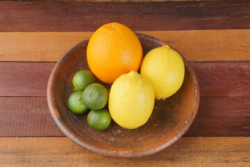 various types of oranges on a clay plate over a wooden background with studio lighting