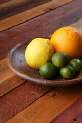 various types of oranges on a clay plate over a wooden background with studio lighting