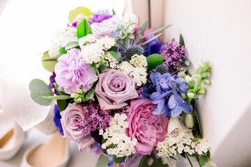 A gorgeous assortment of purple and pink flowers in an arrangement by a windowsill. 