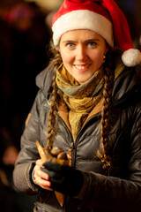 attraktive Frau mit Nikolausmütze , auf dem Weihnachtsmarkt, am Maronenstand.