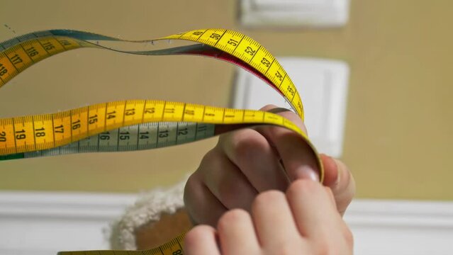vertical video close-up in a sewing workshop the hands of seamstress hold a yellow centimeter
