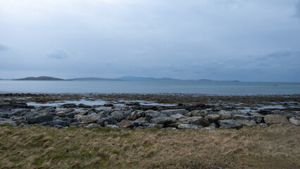Scenic view of ocean at low tide with rocks and seaweed on the remote island of South Uist in the...