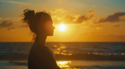 A silhouette of woman to be gazing at the horizon as the sky transitions into shades of orange. clouds