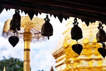 A row of bells hanging from a building. The scene is peaceful and serene