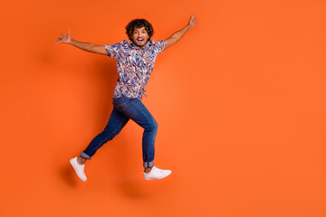 Full body photo of attractive young man running excited dressed stylish colorful clothes isolated on orange color background