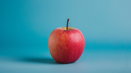 Red apple on solid blue background, commercial photography style