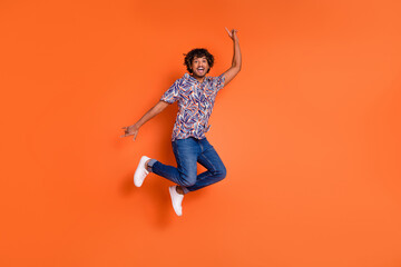 Full length photo of handsome young man jump point up empty space dressed stylish colorful garment isolated on orange color background