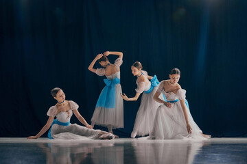 Serene scene of four ballet dancers, each in different pose, wearing ethereal white dresses with...