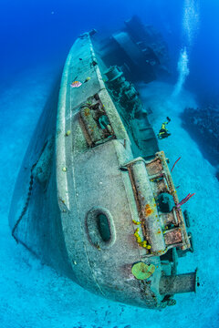 Scuba diver swimming alongside the bow of the Kittiwake shipwreck on the seabed, Seven Mile Beach, Grand Cayman, Cayman Islands, Caribbean Sea. 