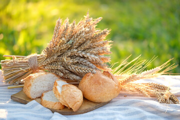 baked breads and wheat ears on table in garden close up, natural background. Bread making, bakery, healthy organic food concept