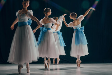 Portrait of four young ballerinas, posing in graceful positions, dressed in delicate white tutus...