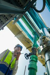 Industrial engineer adjusting pipeline valve with radio communication on construction site....