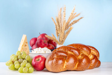 Happy Shavuot holiday background with summer red apples, wheat, grapes, dairy products - cheese,...