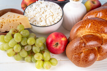 Happy Shavuot holiday background with summer red apples, wheat, grapes, dairy products - cheese, cottage cheese, milk or cream, copy space for text