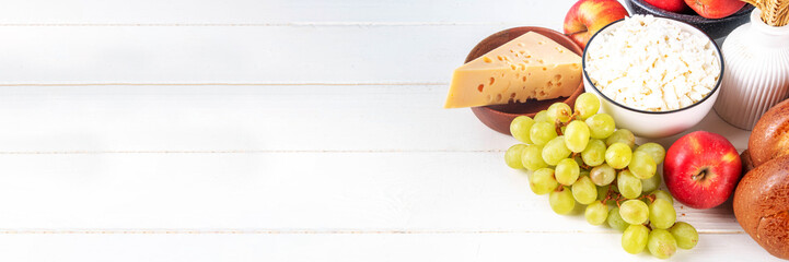 Happy Shavuot holiday background with summer red apples, wheat, grapes, dairy products - cheese, cottage cheese, milk or cream, copy space for text
