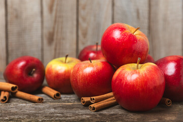 Apples with cinnamon on a textured wooden background. Fragrant red spiced apples with cinnamon sticks and star anise. Apple slices with spicy spices. Place for text. Copy space. Harvesting. Fruits. 