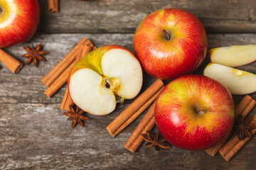 Apples with cinnamon on a textured wooden background. Fragrant red spiced apples with cinnamon sticks and star anise. Apple slices with spicy spices. Place for text. Copy space. Harvesting. Fruits. 