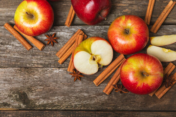 Apples with cinnamon on a textured wooden background. Fragrant red spiced apples with cinnamon sticks and star anise. Apple slices with spicy spices. Place for text. Copy space. Harvesting. Fruits. 