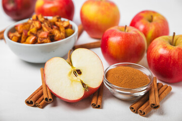 Apples with cinnamon on a textured wooden background. Fragrant red spiced apples with cinnamon sticks and star anise. Apple slices with spicy spices. Place for text. Copy space. Harvesting. Fruits. 