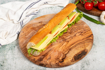 Cheddar sandwich on wood serving board. Sandwich made with tomatoes, cucumber, greens, cheddar cheese and special sauce