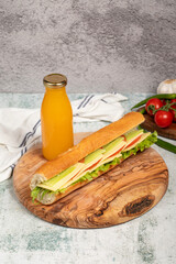 Cheddar sandwich on wood serving board. Sandwich made with tomatoes, cucumber, greens, cheddar cheese and special sauce