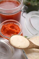 Spoon with fresh marinade over table, closeup