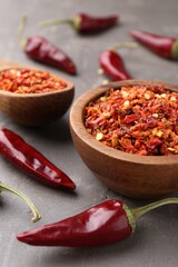 Chili pepper flakes and pods on grey table, closeup