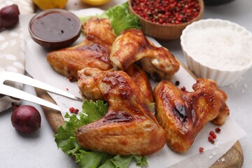 Fresh marinated chicken wings, spices and lettuce on light table, closeup