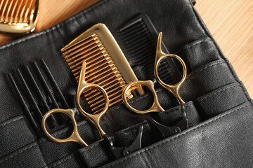 Hairdresser tools. Professional scissors and combs in leather organizer on wooden table, top view