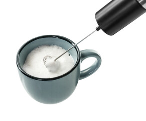 Whisking milk in cup with mini mixer (frother wand) isolated on white, closeup