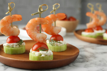 Tasty canapes with shrimps, vegetables and cream cheese on white marble table, closeup