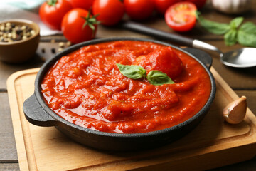 Homemade tomato sauce and basil in bowl on wooden table, closeup