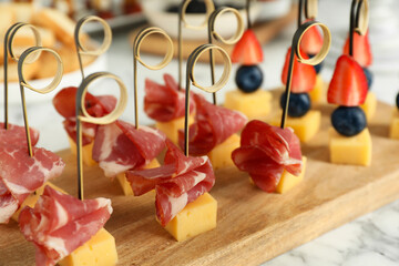 Different tasty canapes on white marble table, closeup
