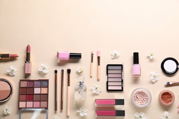 Flat lay composition with different makeup products and beautiful spring flowers on beige...
