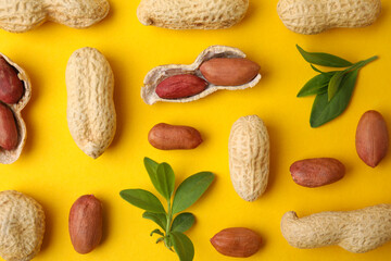 Fresh peanuts and leaves on yellow table, flat lay