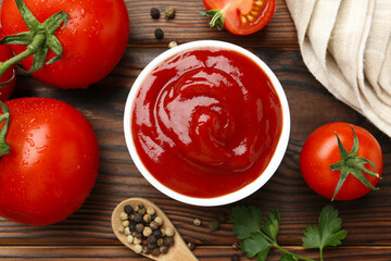 Delicious ketchup in bowl, tomatoes and peppercorns on wooden table, flat lay