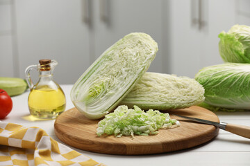 Fresh Chinese cabbages, knife and oil on white wooden table in kitchen