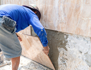 Tiling man laying marble texture tiles on the wall