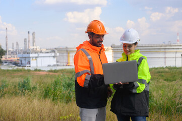 Two male and female engineers are discussing the operation of a refinery storage tank.