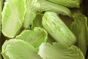 Pouring tap water on Chinese cabbage leaves in sink, top view