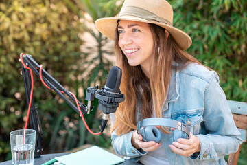 Attractive woman recording radio podcast - Young girl talking during live stream session outdoor....