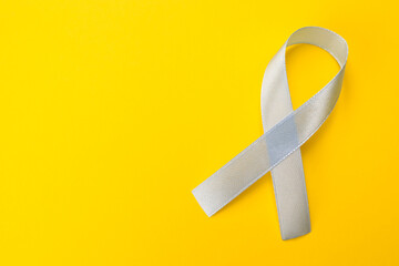 International Psoriasis Day. Ribbon as symbol of support on yellow background, top view. Space for...