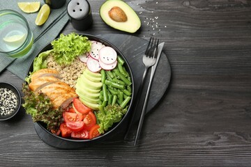Healthy meal. Tasty products in bowl and cutlery on black wooden table, flat lay. Space for text