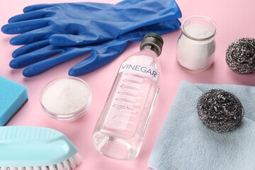 Eco friendly natural cleaners. Vinegar in bottle, soda, brushes and gloves on pink background