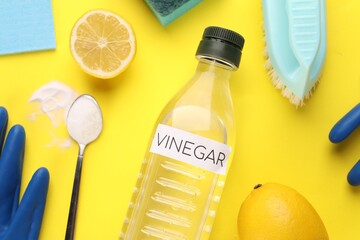 Eco friendly natural cleaners. Flat lay composition with bottle of vinegar on yellow background