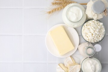 Different dairy products and spikes on white tiled table, flat lay. Space for text