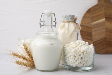 Different dairy products and spikes on white tiled table