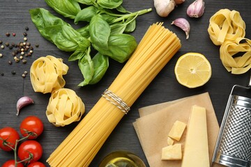 Different types of pasta, products, peppercorns and garter on dark wooden table, flat lay